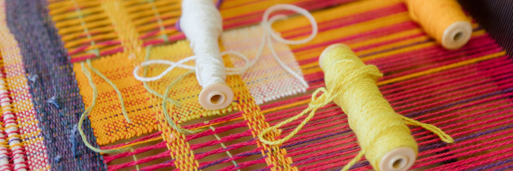 Yarn being woven into fabric on a loom.