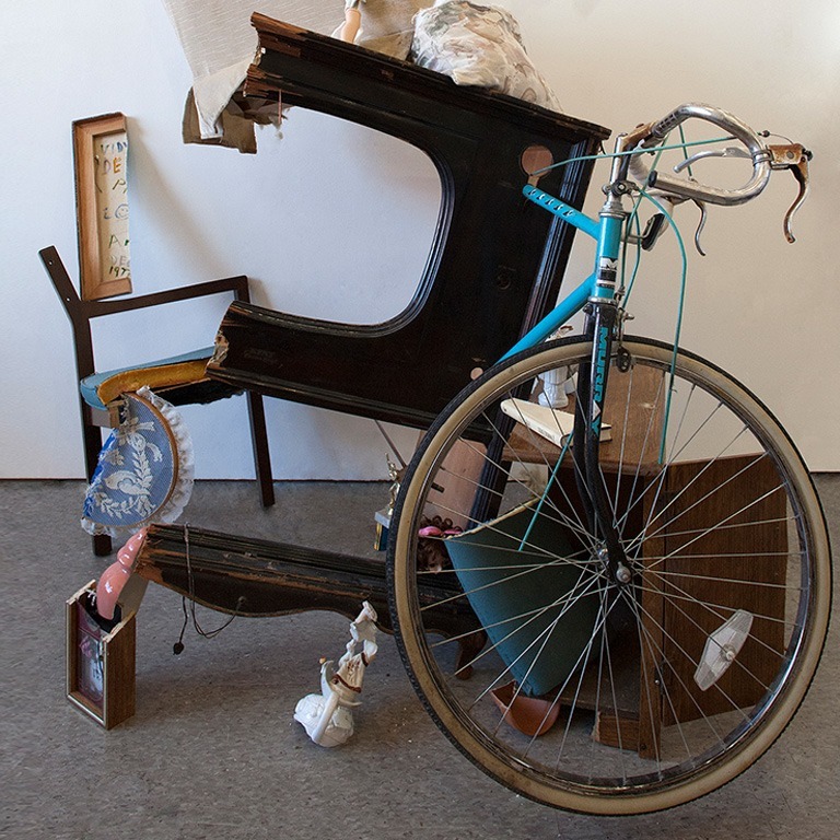 A sculpture featuring a bike wheel and a chair.