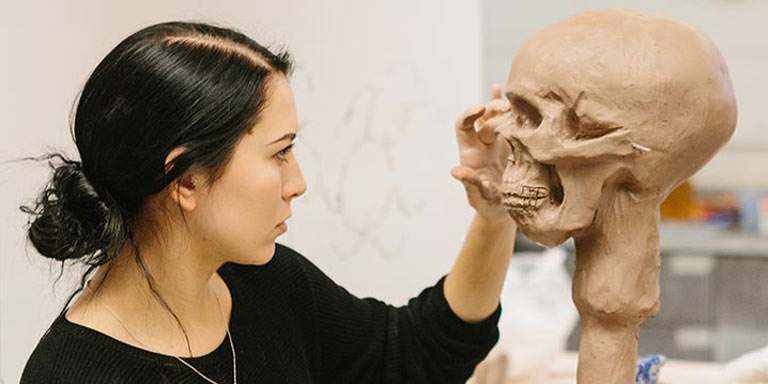 A person works on a sculpture of a face. 