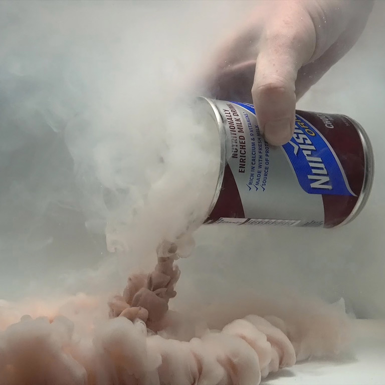A person pours an open can of a brownish substance under water. 