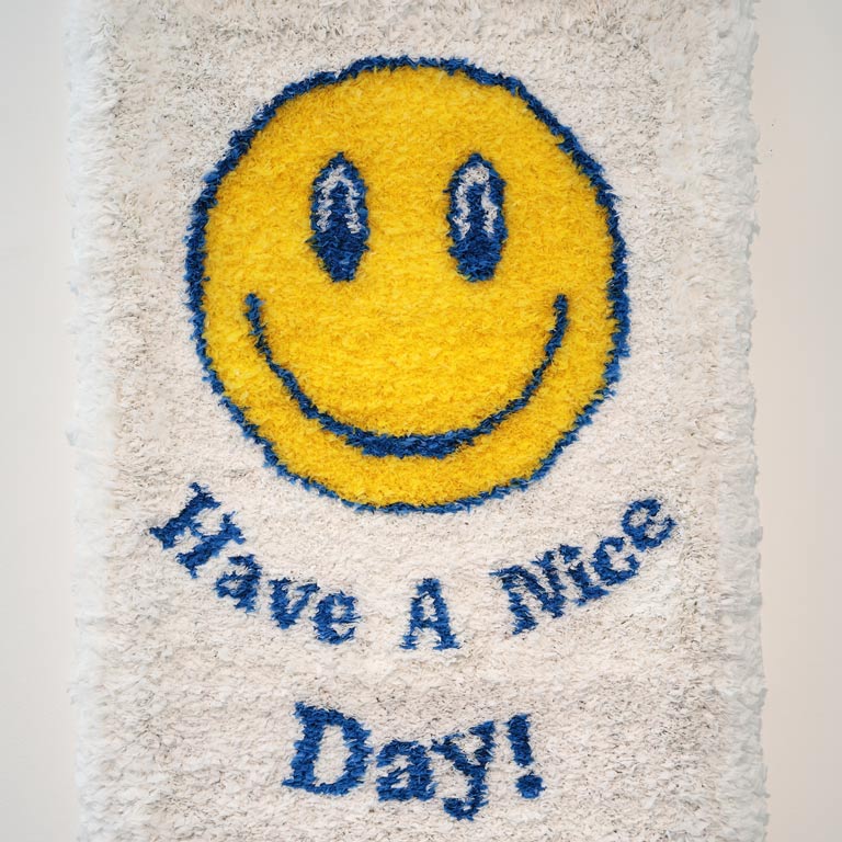 A piece of art made from plastic bags that says Have a Nice Day around a smiley face. 
