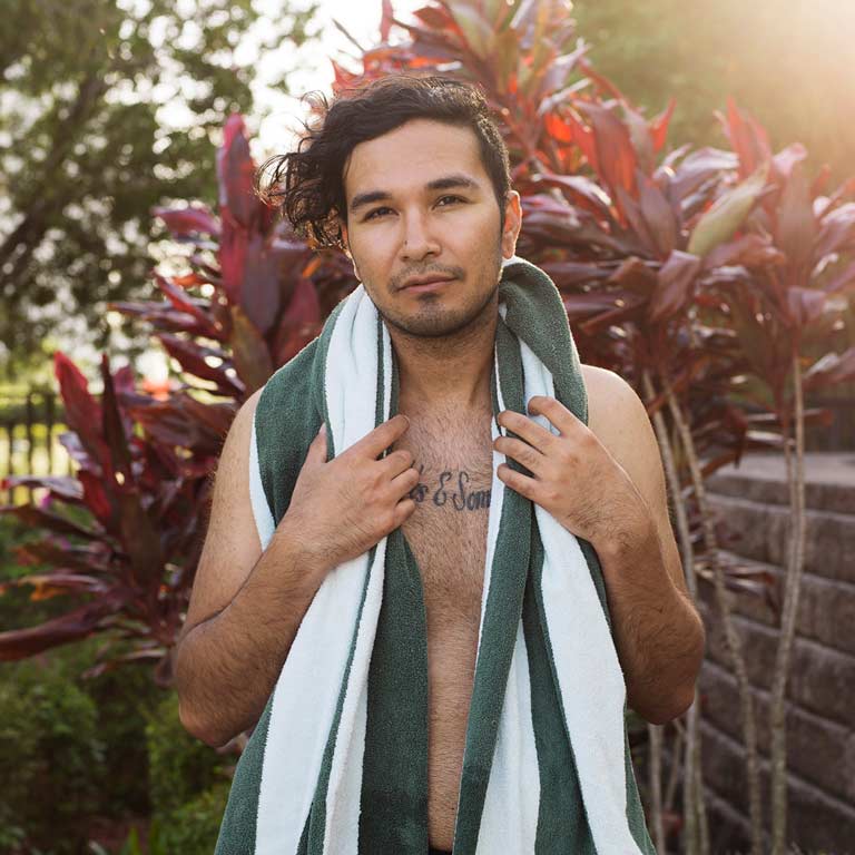 A person with a towel over bare shoulders looks at the camera.