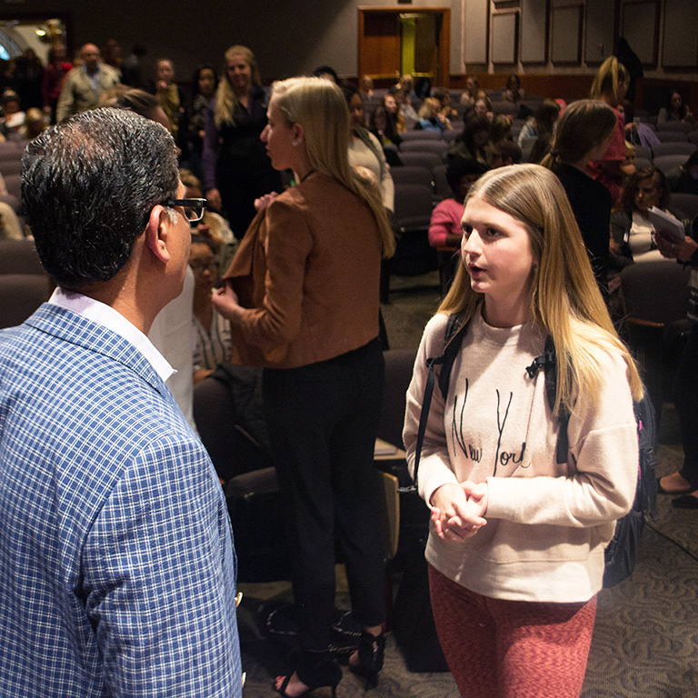 Two people talk in a crowded room.