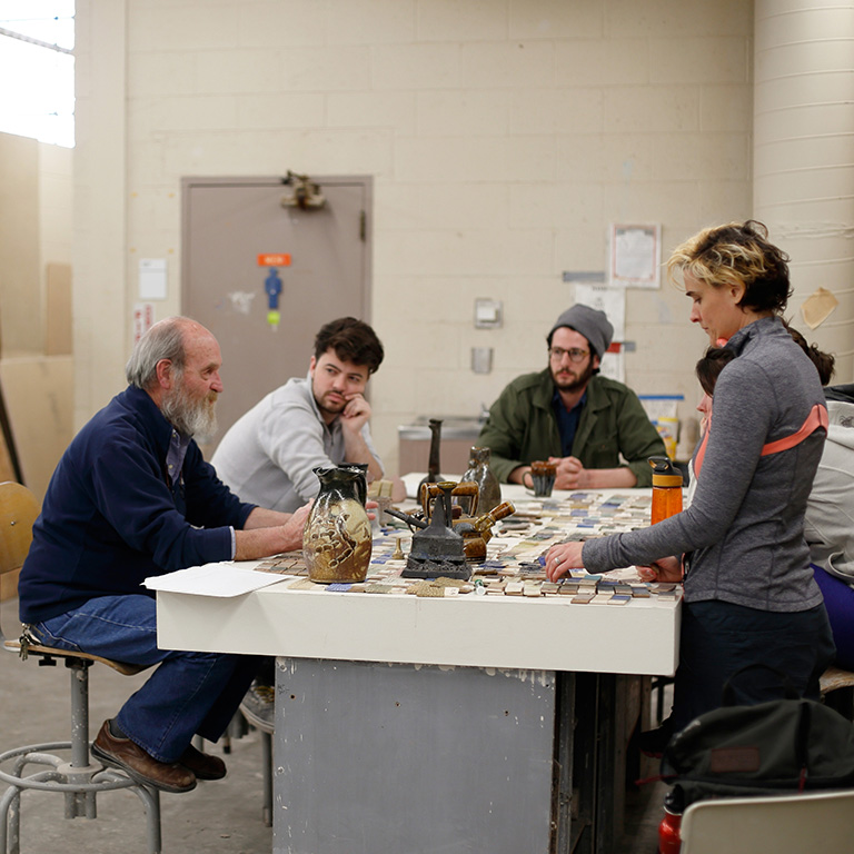 People sit around a table in a ceramics studio.