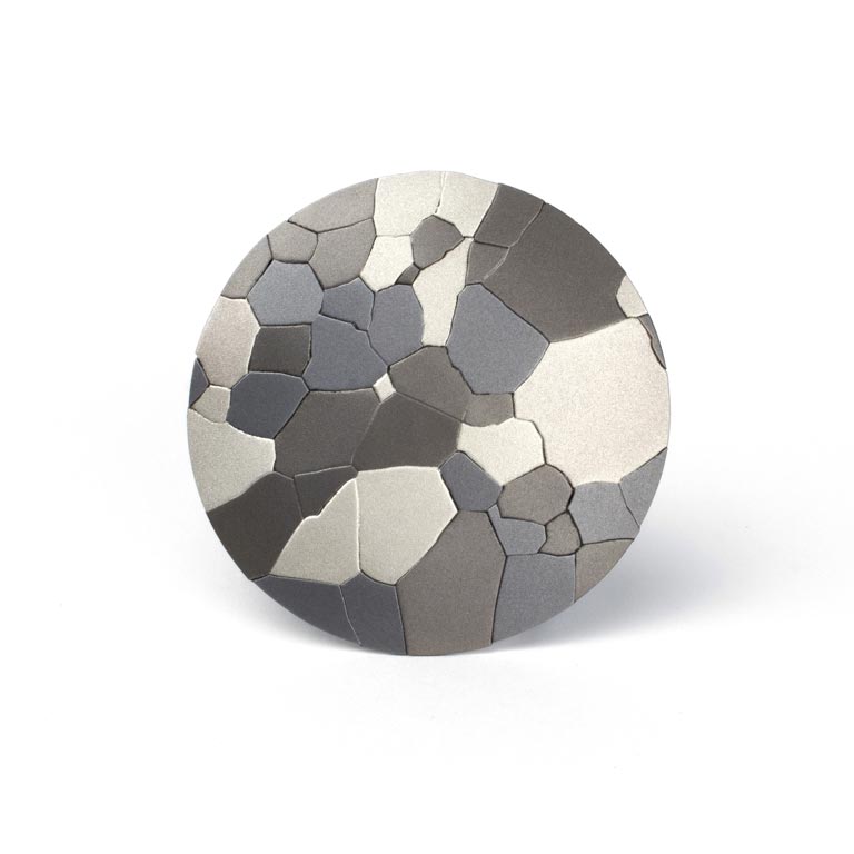 A brooch created with titanium, sterling silver, and steel. 