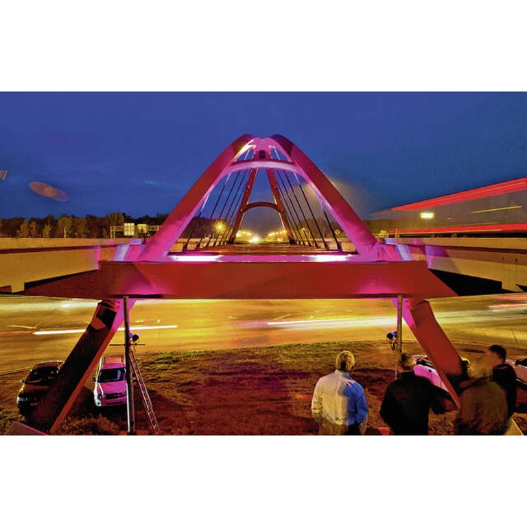 A long exposure image of the red bridge in Columbus, Indiana lit at night by cars driving underneath it.