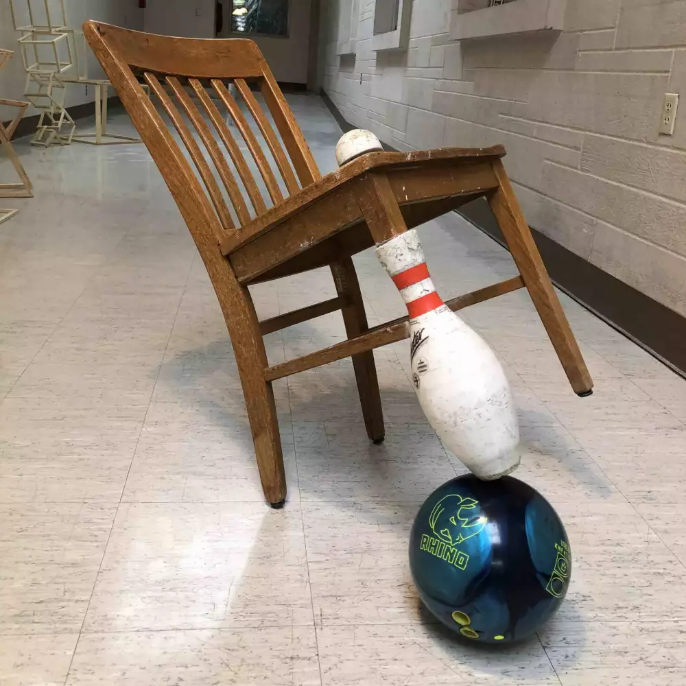 A bowling pin on top of a bowling ball repurposed as a chair leg.
