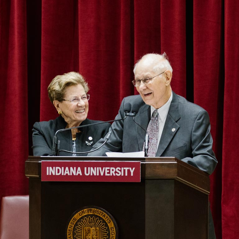 Two people smile at a podium. 
