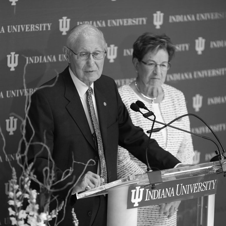 Two people stand in front of an Indiana University backdrop