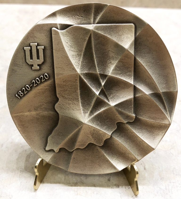 A round medallion with the IU trident and 1820–1920 written on it
