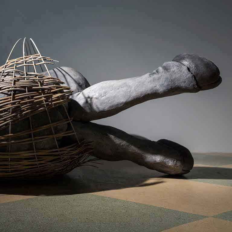 Sculpture of animal legs coming out of a basket structure.