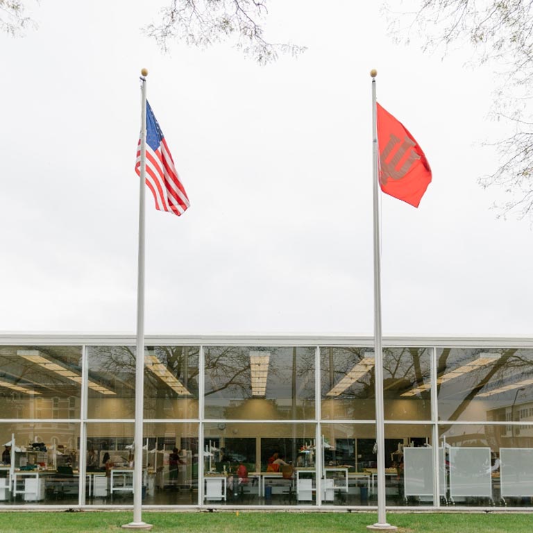 Two flags in front of a glass building.